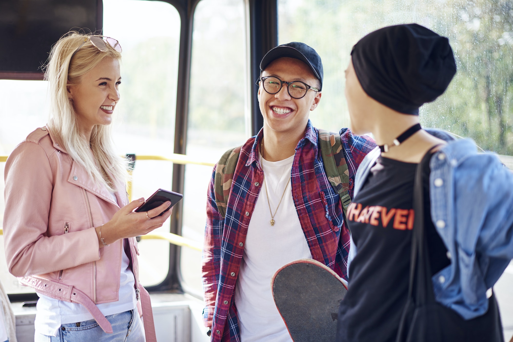 Three young adult friends chatting on city tram